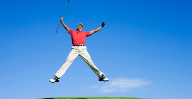 Enthusiastic golfer jumps in the air with excitement after getting a hole in one.