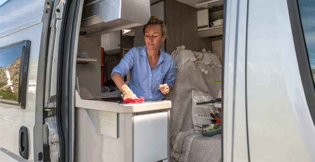 Woman washing the stove in her motorhome with the door open.