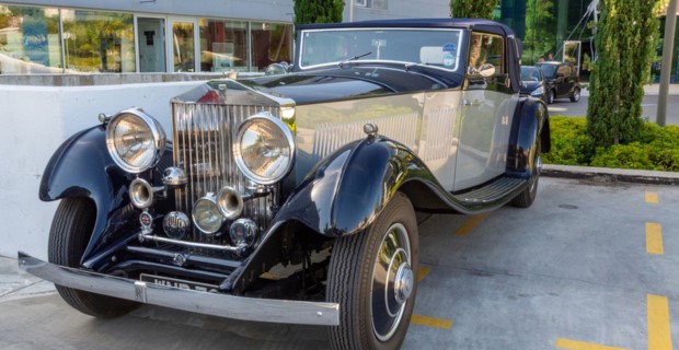 A classic Bentley with elegant blue and grey hues is parked next to a building.