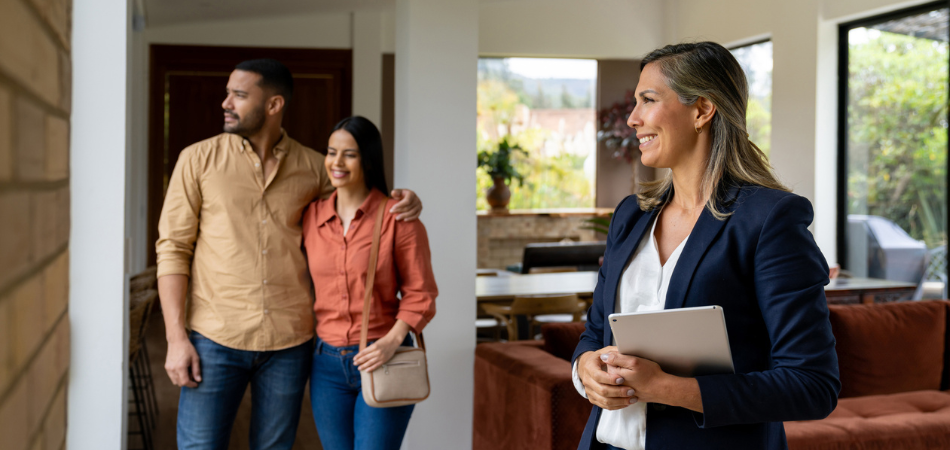 A couple tours a new home with a real estate agent, symbolizing the process of buying your first home.