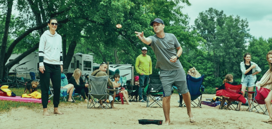 Man playing the game of washers at a campground.