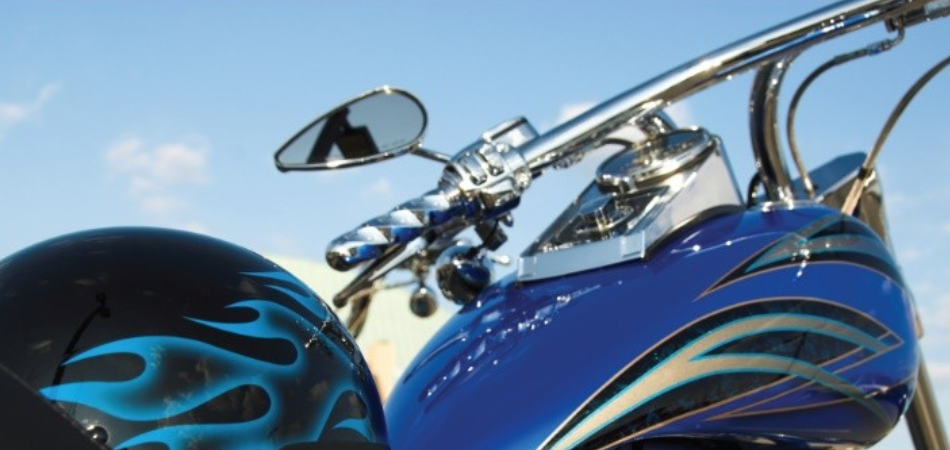 Close-up of a blue motorcycle with chrome parts and flame decals on the tank and helmet.