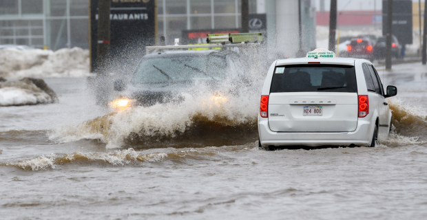 Two vehicles driving through a flooded downtown area.