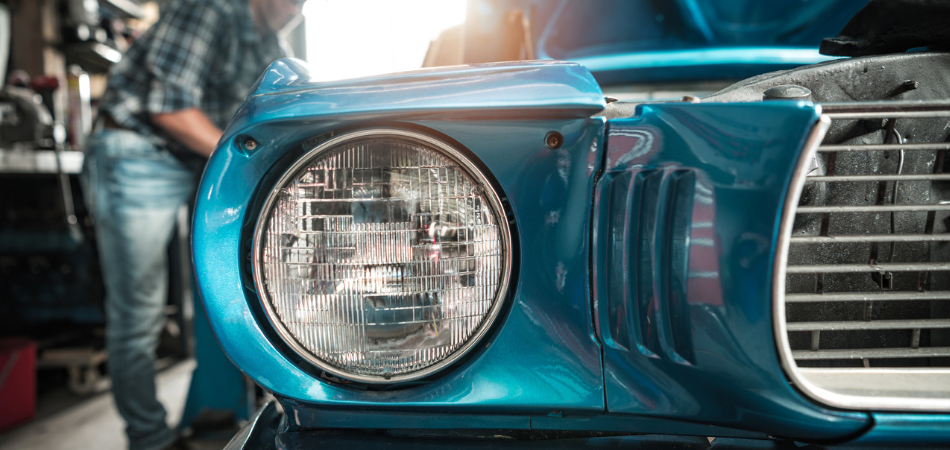 Close-up of a blue classic car’s headlight in a garage, illustrating tips for storing your classic car over the winter.