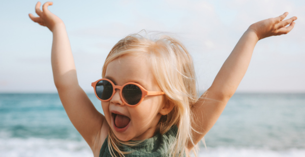 Young girl posing for a picture on the beach with her hands in the air