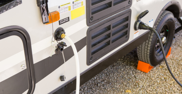 Filling the water tank of an RV in campground area.