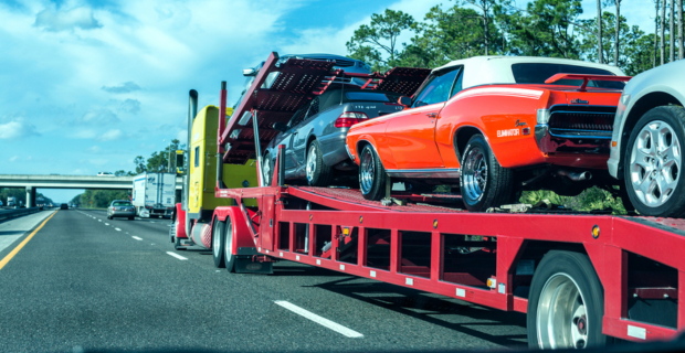 A flatbed trailer delivering a Honda Accord, a Mercedes-Benz CLK 430 convertible, a  Ford Fusion family sedan, and a 1960's Mercury Cougar Eliminator muscle car convertible.