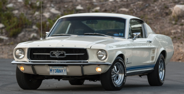 A cream colour Ford mustang parked outside. 