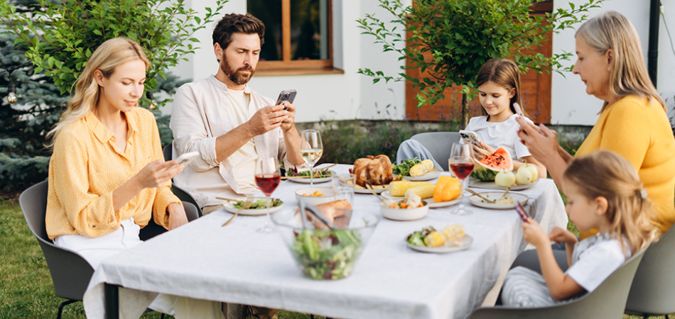 A family gathered around the table for a meal, with each member absorbed in their screen.
