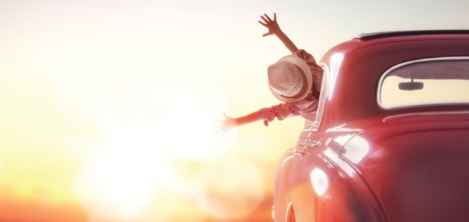 A young woman is happy and proud behind the wheel of her Beetle