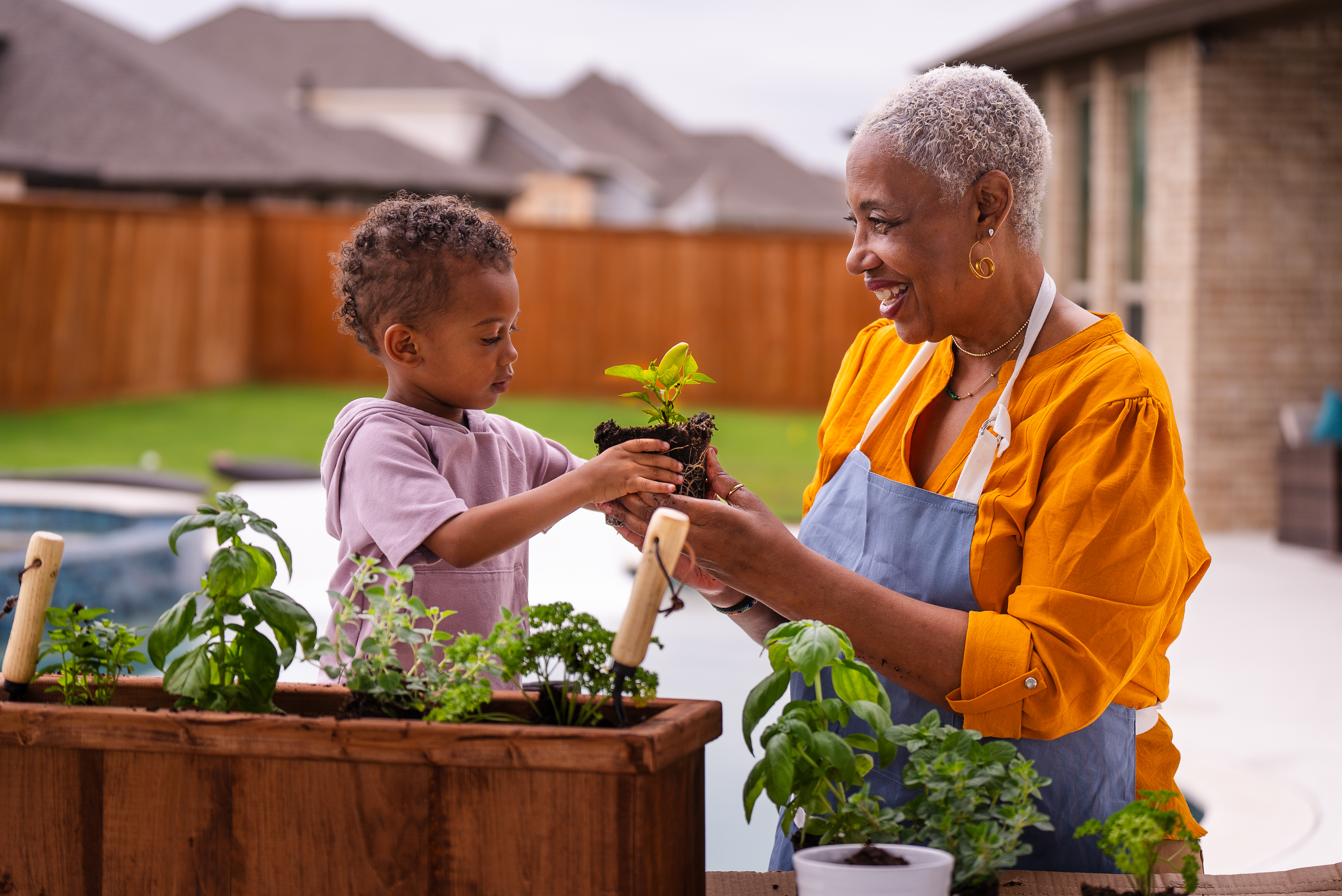 A grandmother gardening outside with her grandchild