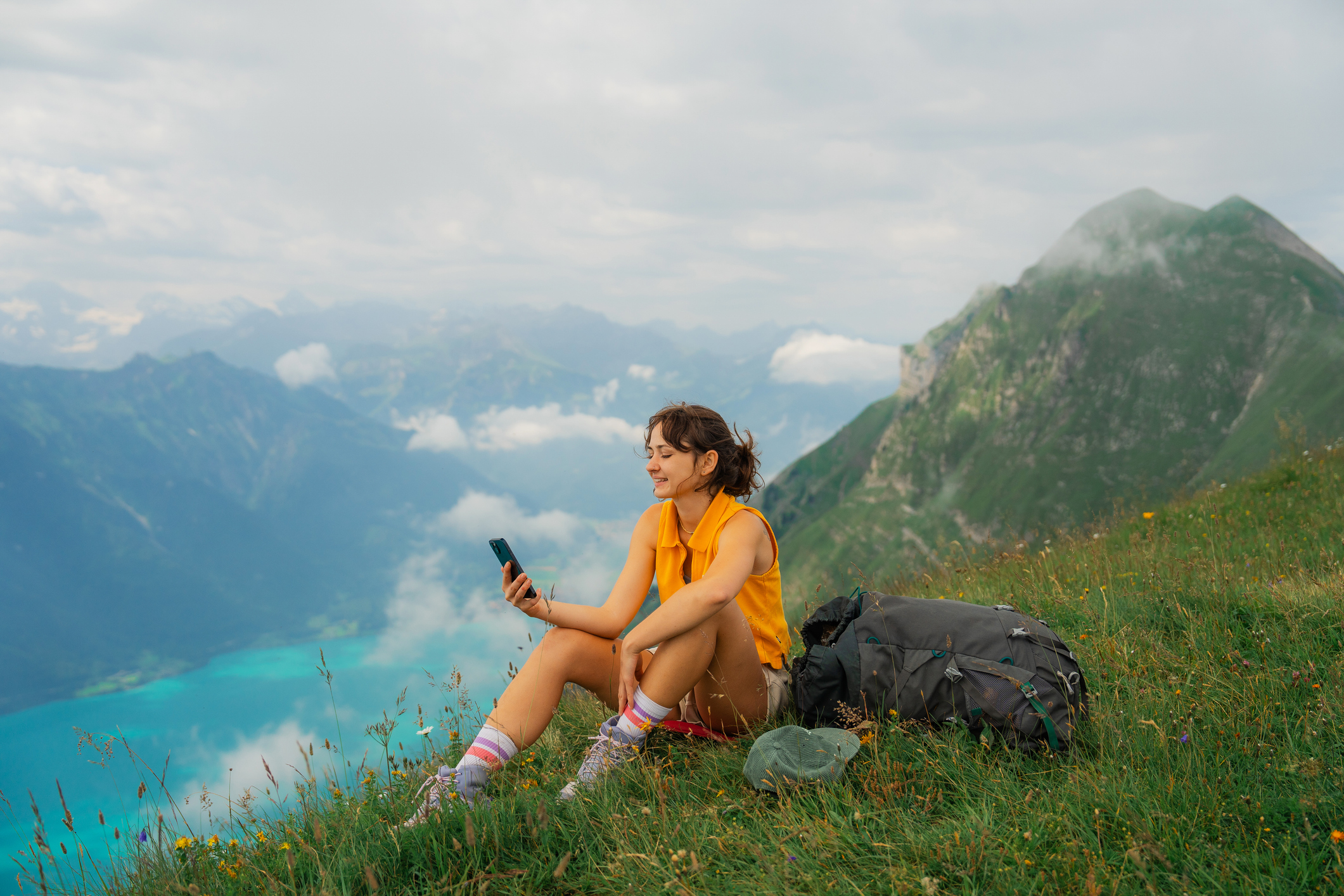 A woman sitting in the mountains checking her smart phone