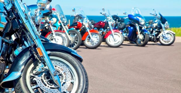 Motorcycles lined up on pavement on a sunny day