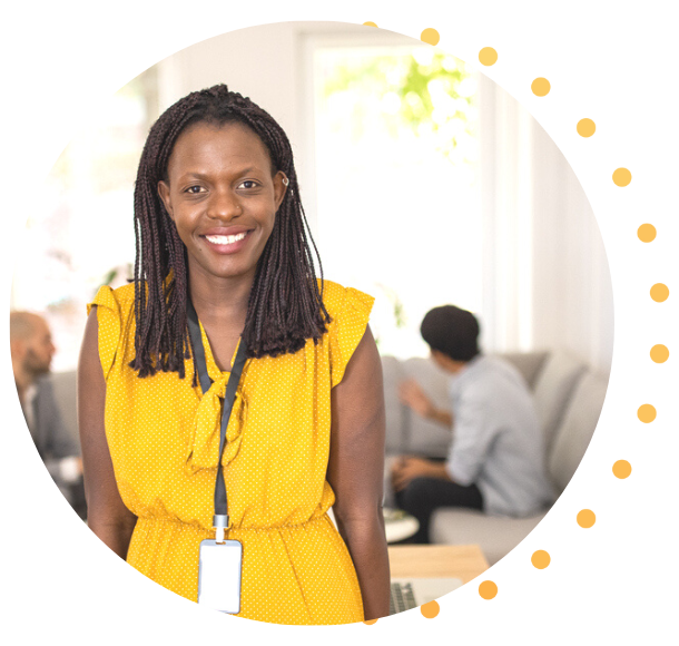 A Black woman in an orange dress is wearing a lanyard with her badge on it, smiling at the camera.