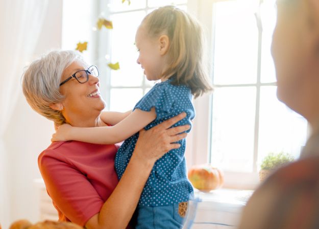 A grandmother hugging her granddaughter at a family dinner.