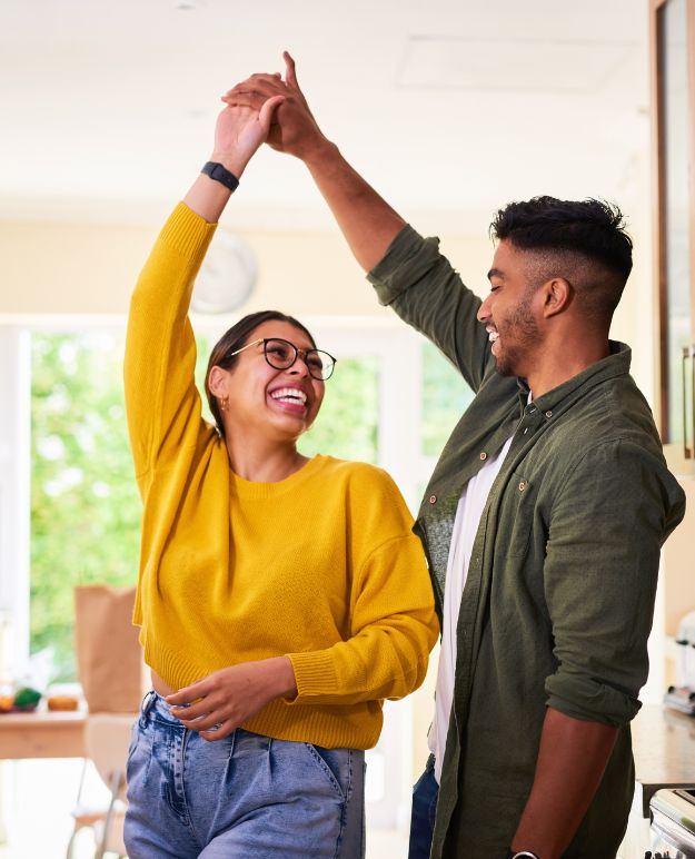 A couple dancing together in the kitchen of their new home.