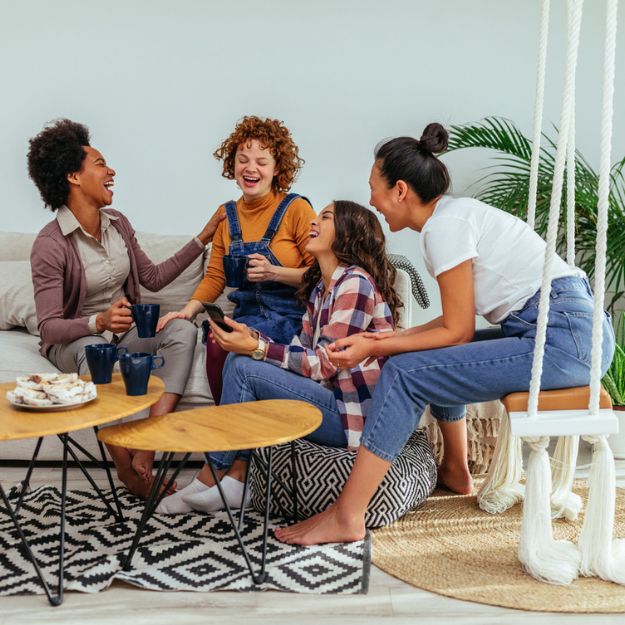 A group of five friends gathered around a kitchen island enjoying lively conversation.