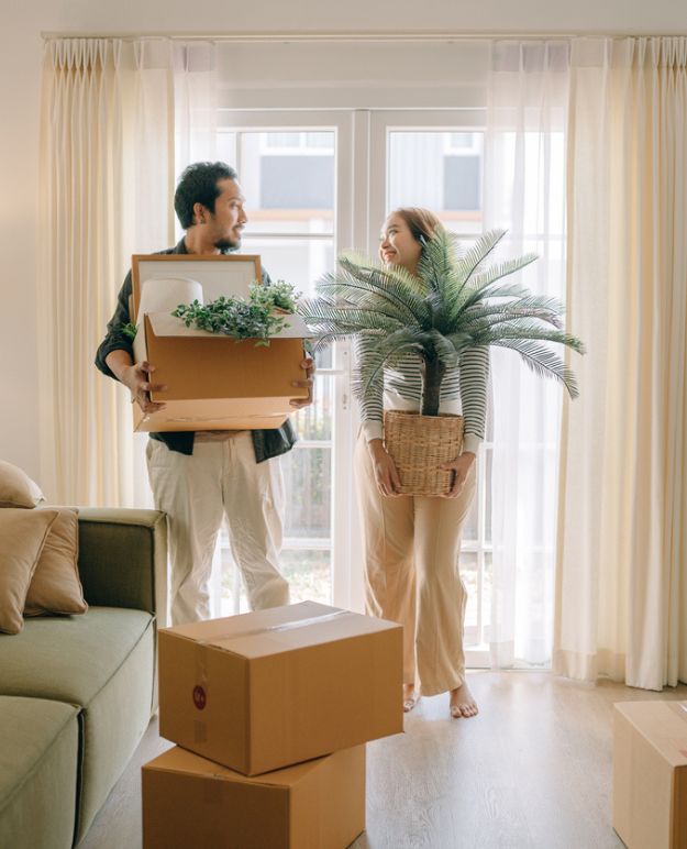 A couple carrying boxes into their new apartment.