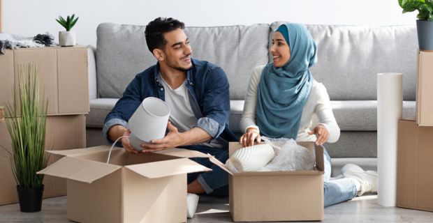 A couple unpacking boxes in the living room of their new home.