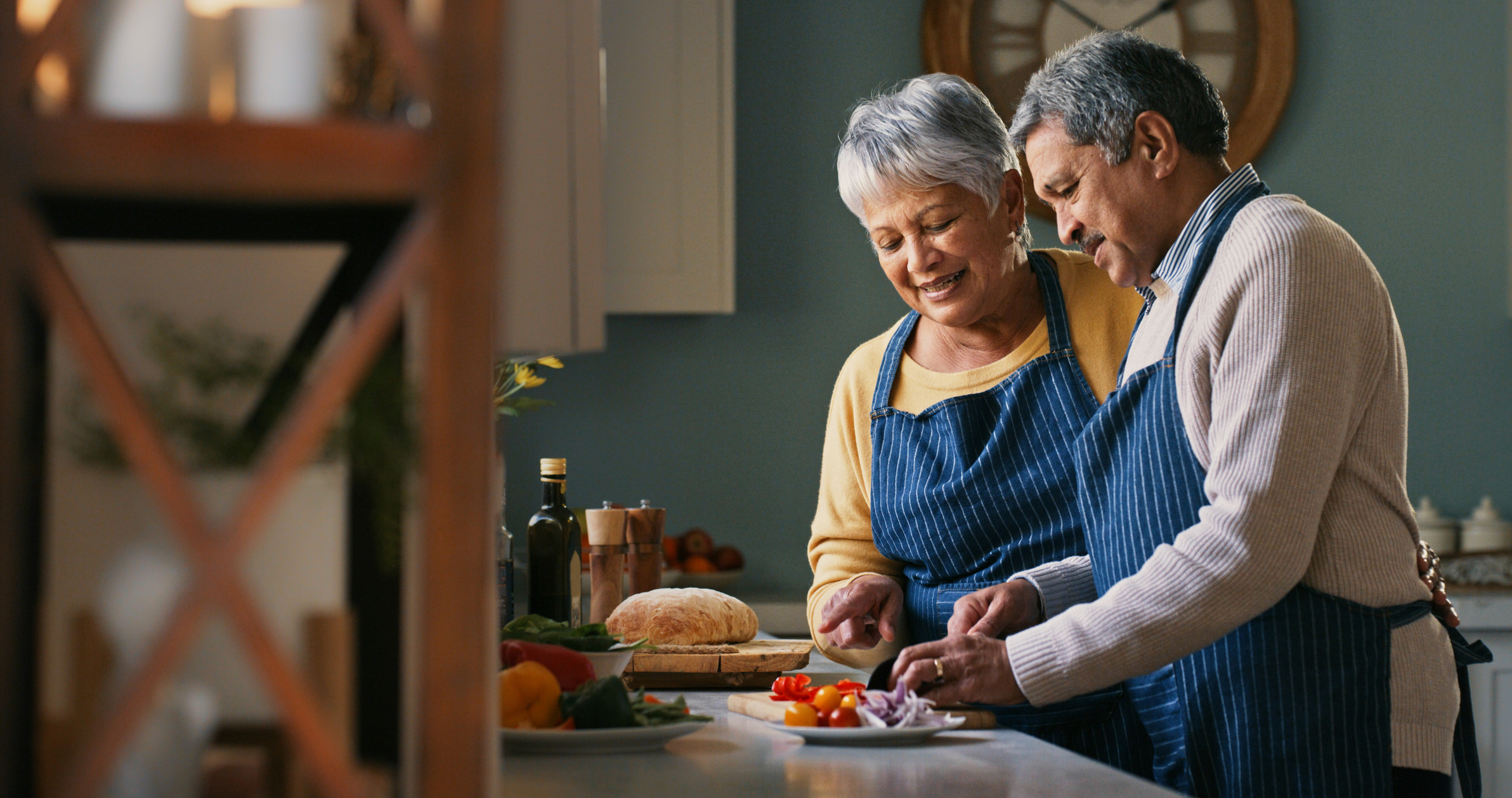 Mature couple chopping vegetables in kitchen at home