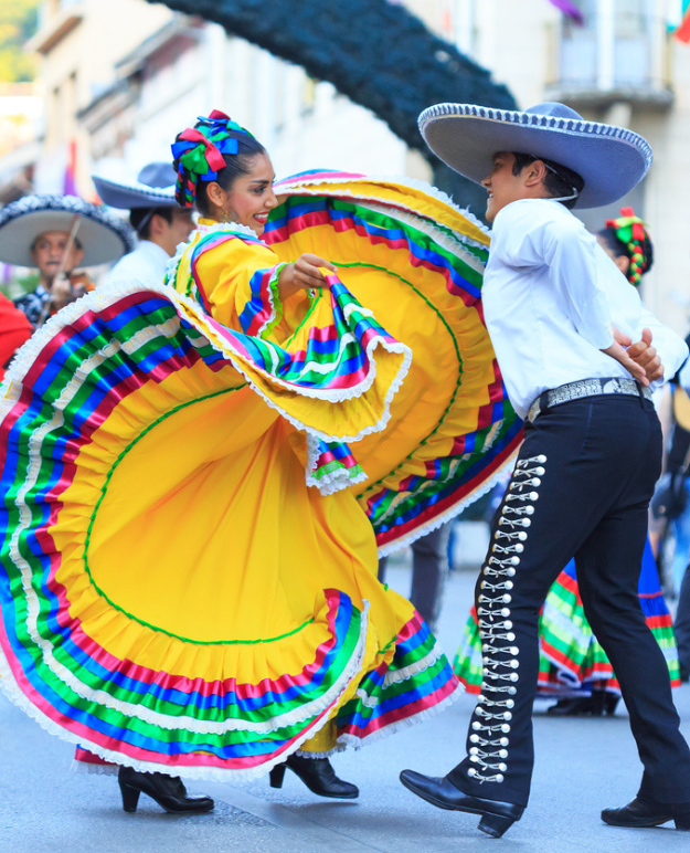 Dancers in traditional Mexican garb perform on the street during a festival in Mexico.