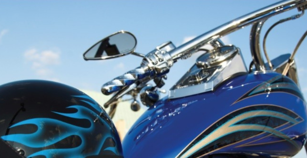 Close-up of a blue motorcycle with chrome parts and flame decals on the tank and helmet.