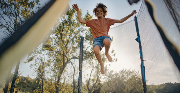 Young person bouncing and enjoying their trampoline in the summer. 