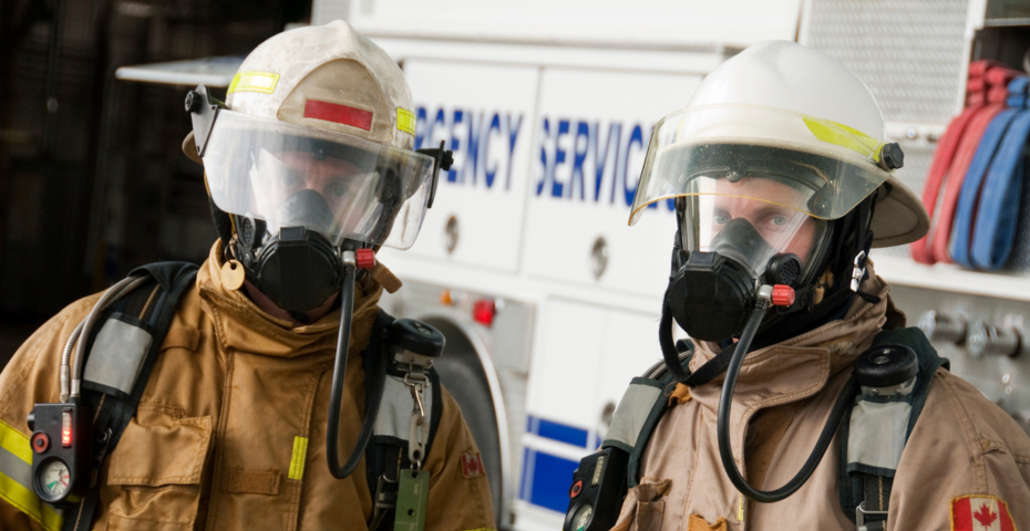 Two Canadian firefighters in front of their firetruck in full gear talking about FireSmart and sharing top fire prevention tips