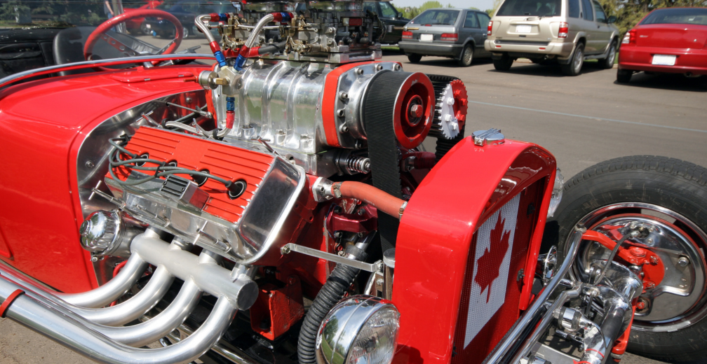 A high-performance red coloured street rod with aftermarket auto parts and a Canadian flag on the front.